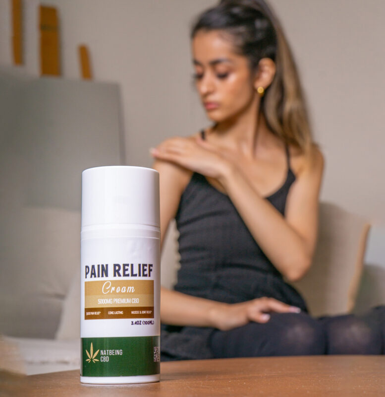 a woman applying cbd cream on her shoulder