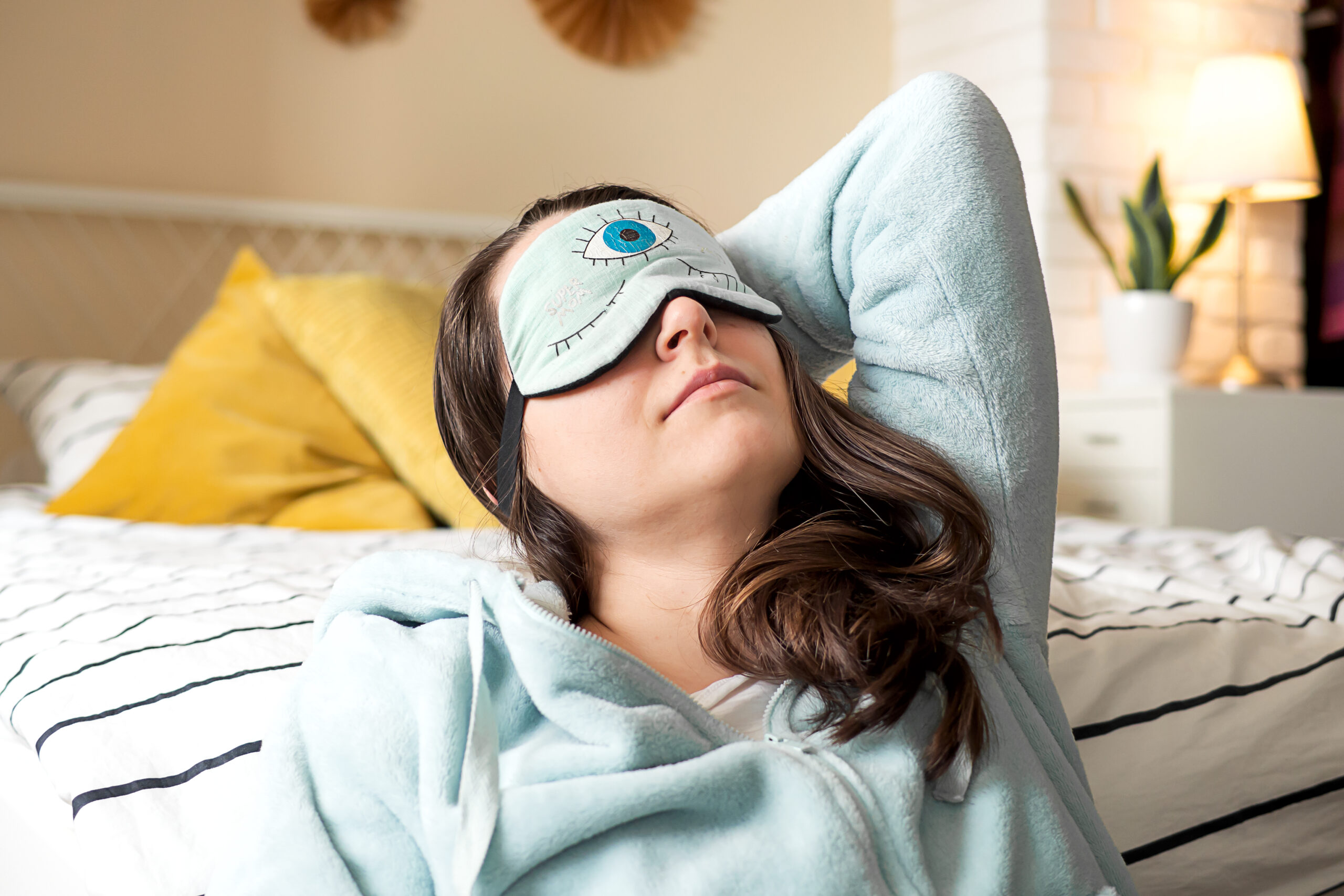 middle aged woman pajamas sleep mask sitting relaxed bed home scaled